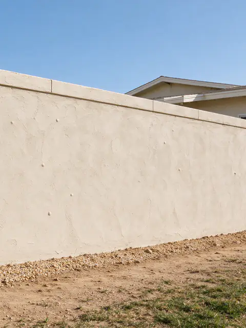 Freestanding concrete block privacy wall with a smooth stucco finish and a flat cap along a level San Diego side yard